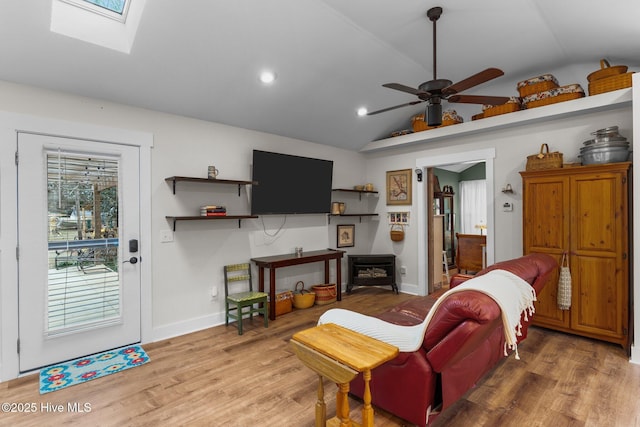 living room featuring hardwood / wood-style flooring, lofted ceiling with skylight, and ceiling fan