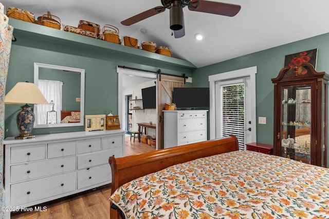 bedroom with lofted ceiling, access to exterior, light hardwood / wood-style floors, and a barn door