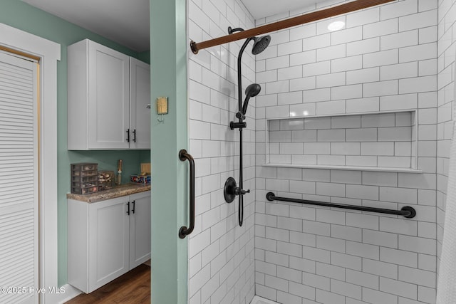 bathroom with hardwood / wood-style flooring and tiled shower