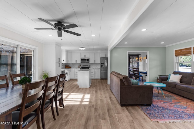 living room featuring ceiling fan, ornamental molding, and light hardwood / wood-style floors