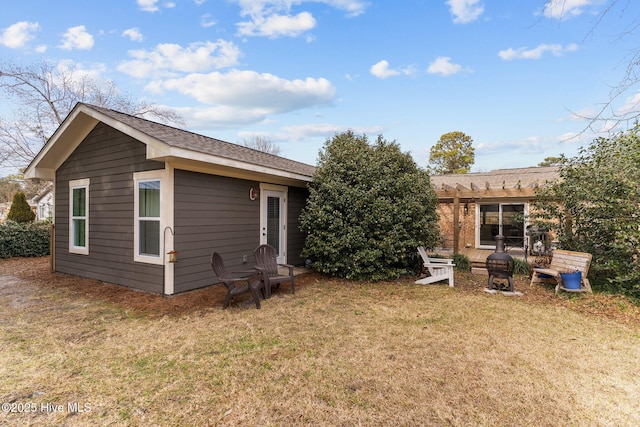 rear view of property featuring a yard and a pergola