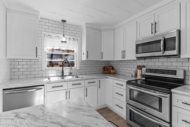 kitchen featuring sink, white cabinetry, tasteful backsplash, hanging light fixtures, and appliances with stainless steel finishes