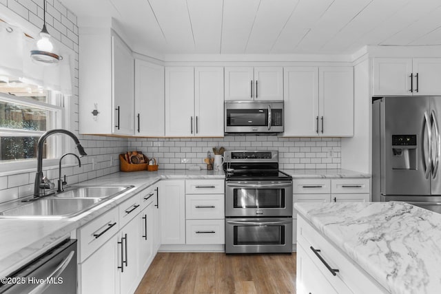 kitchen with sink, white cabinetry, backsplash, hardwood / wood-style floors, and stainless steel appliances