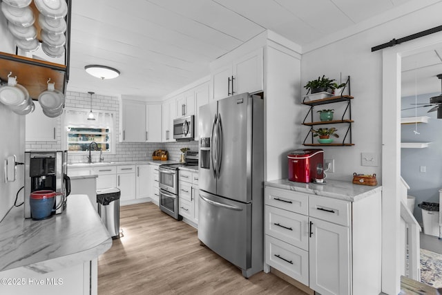 kitchen featuring sink, stainless steel appliances, tasteful backsplash, white cabinets, and light wood-type flooring