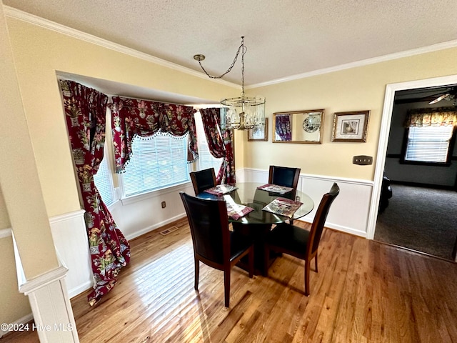 dining area with hardwood / wood-style floors, a textured ceiling, and ornamental molding