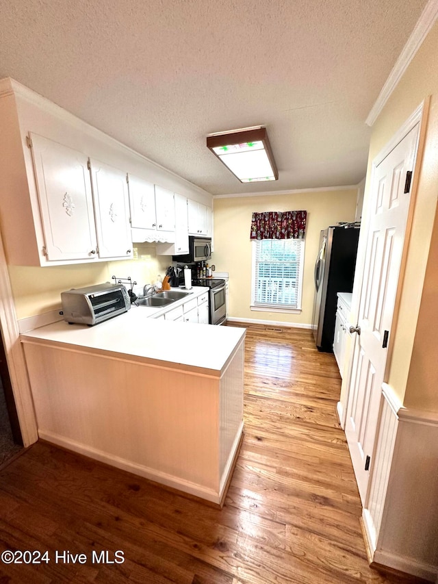 kitchen featuring kitchen peninsula, appliances with stainless steel finishes, a textured ceiling, light hardwood / wood-style flooring, and white cabinetry