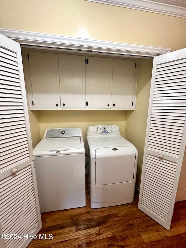 laundry area featuring dark hardwood / wood-style flooring, washer and dryer, and cabinets