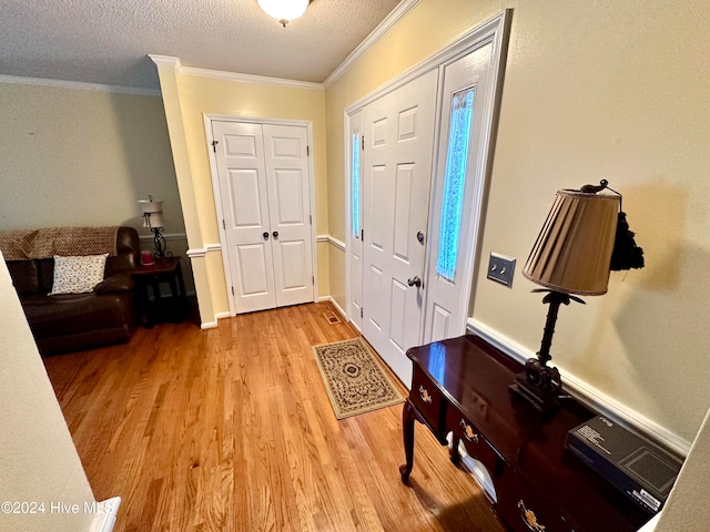 foyer entrance featuring a textured ceiling, light hardwood / wood-style floors, and crown molding