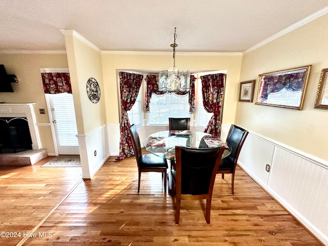 dining room with a chandelier, wood-type flooring, a textured ceiling, and ornamental molding