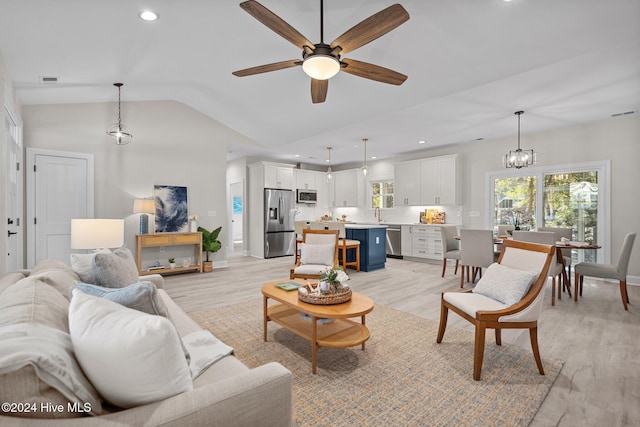 dining area featuring a notable chandelier, lofted ceiling, light wood-type flooring, and sink