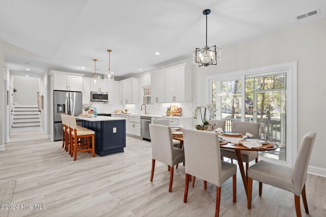 kitchen featuring white cabinetry, sink, tasteful backsplash, light hardwood / wood-style flooring, and appliances with stainless steel finishes