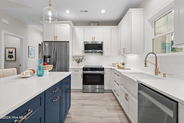 kitchen with stainless steel appliances, white cabinetry, hanging light fixtures, and a kitchen island