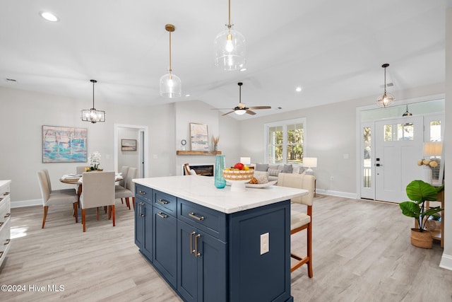 kitchen with a center island, light wood-type flooring, appliances with stainless steel finishes, decorative light fixtures, and white cabinetry