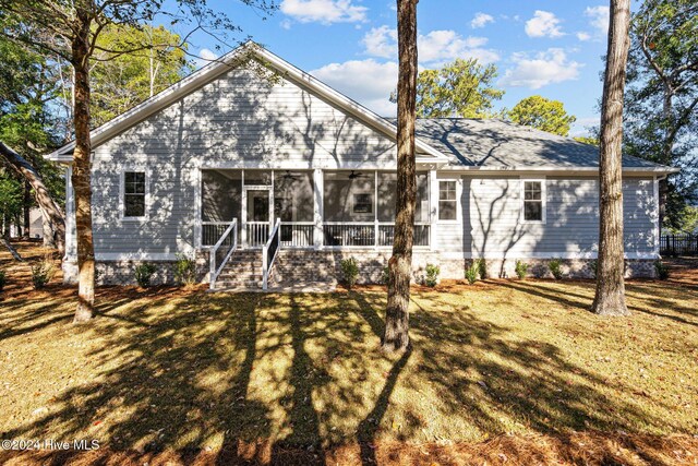 rear view of property featuring a lawn and a sunroom