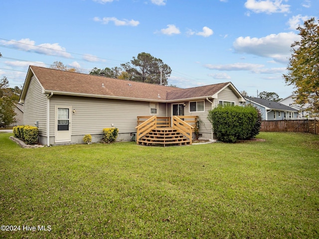 rear view of property featuring a lawn and a wooden deck