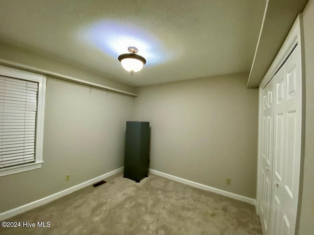 unfurnished bedroom featuring a textured ceiling and light carpet