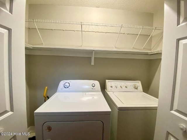 laundry area with independent washer and dryer and a textured ceiling