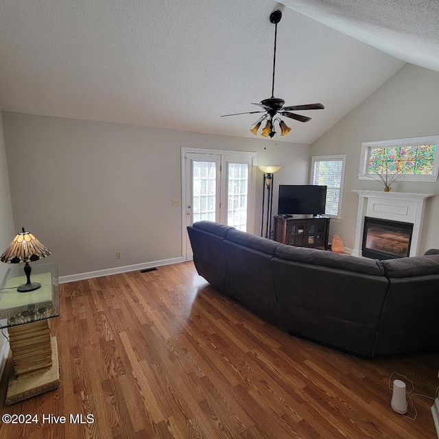 living room with a textured ceiling, hardwood / wood-style flooring, ceiling fan, and lofted ceiling