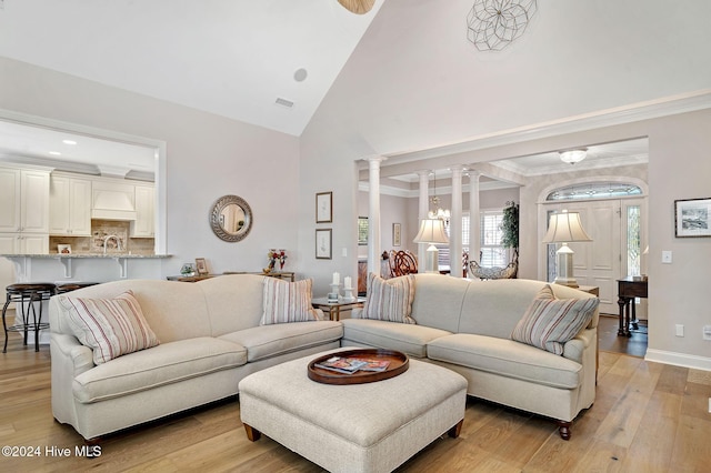 living room featuring light wood-type flooring, vaulted ceiling, and ornate columns