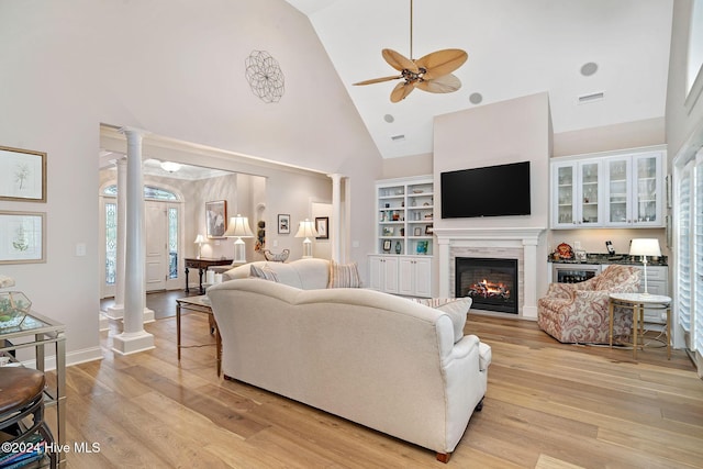 living room featuring high vaulted ceiling, light hardwood / wood-style flooring, and ornate columns