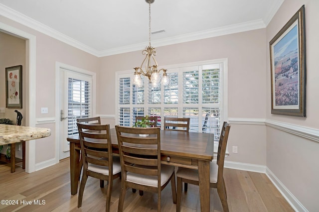 dining space with a healthy amount of sunlight, ornamental molding, a chandelier, and light hardwood / wood-style flooring