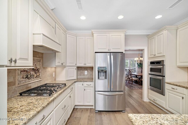 kitchen featuring light stone countertops, crown molding, premium range hood, and appliances with stainless steel finishes