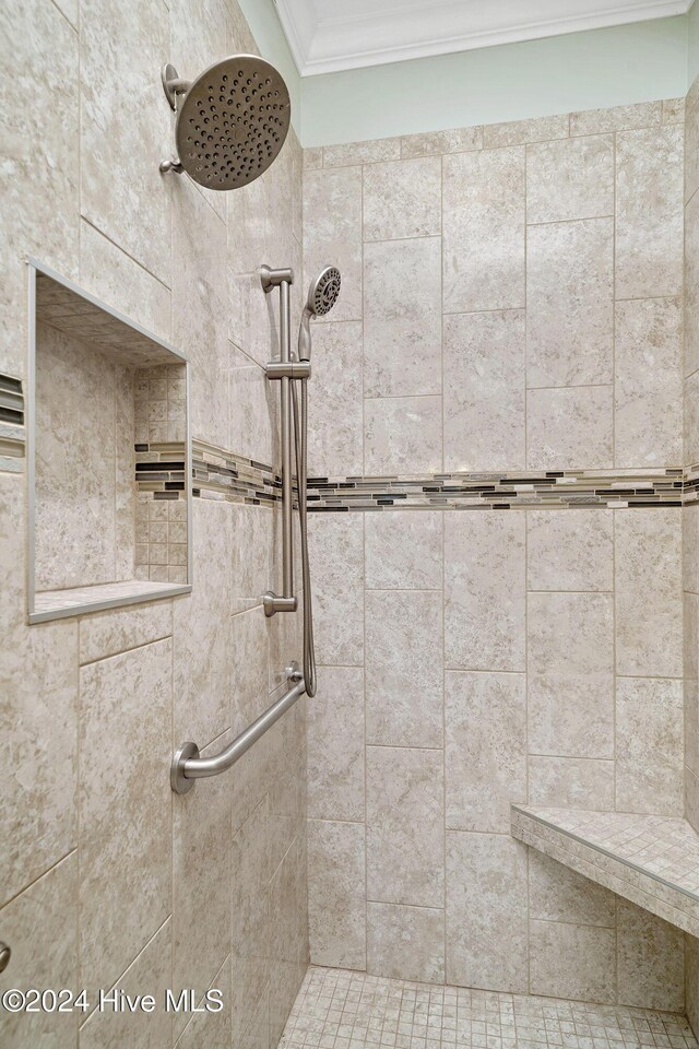 bathroom with a tile shower and crown molding