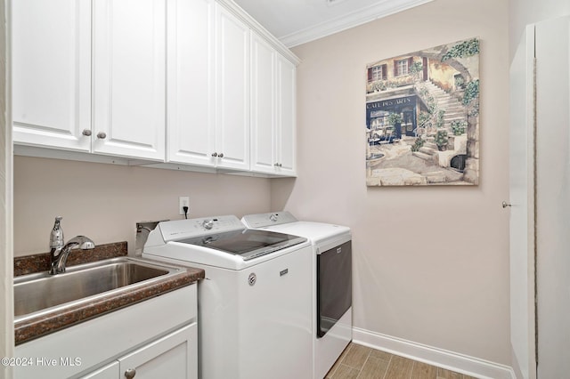 laundry area with cabinets, crown molding, sink, and washing machine and clothes dryer