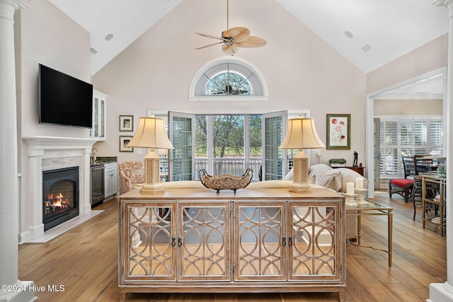 bedroom featuring a high end fireplace, light hardwood / wood-style flooring, and high vaulted ceiling