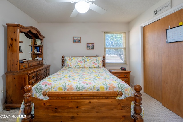 carpeted bedroom featuring ceiling fan and a textured ceiling