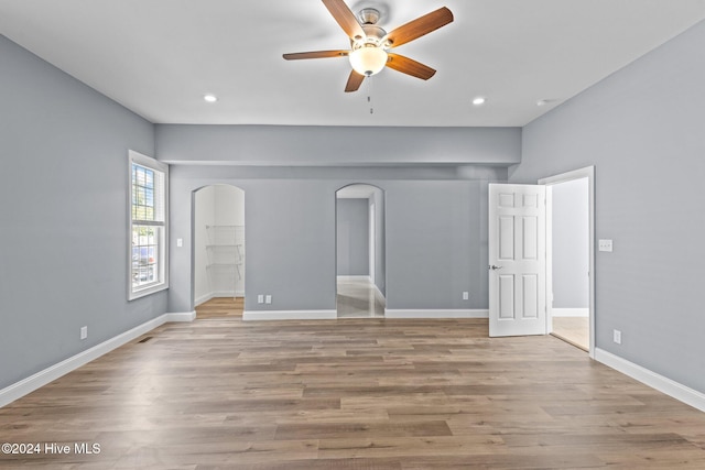 unfurnished bedroom featuring ceiling fan, a spacious closet, and light hardwood / wood-style flooring