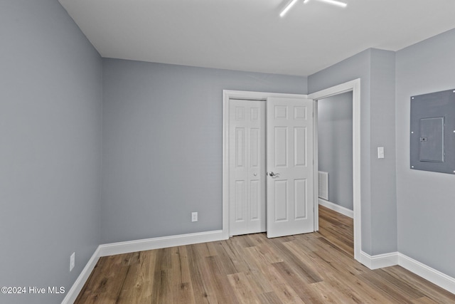 unfurnished bedroom featuring electric panel, light hardwood / wood-style floors, and a closet