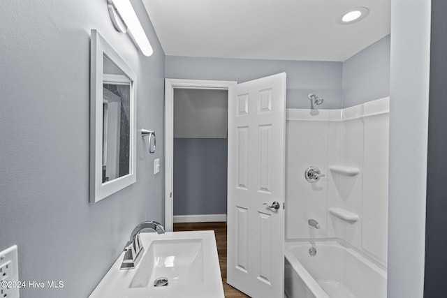 bathroom with wood-type flooring, sink, and bathing tub / shower combination