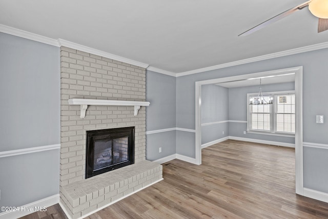 unfurnished living room with hardwood / wood-style floors, crown molding, a fireplace, and an inviting chandelier