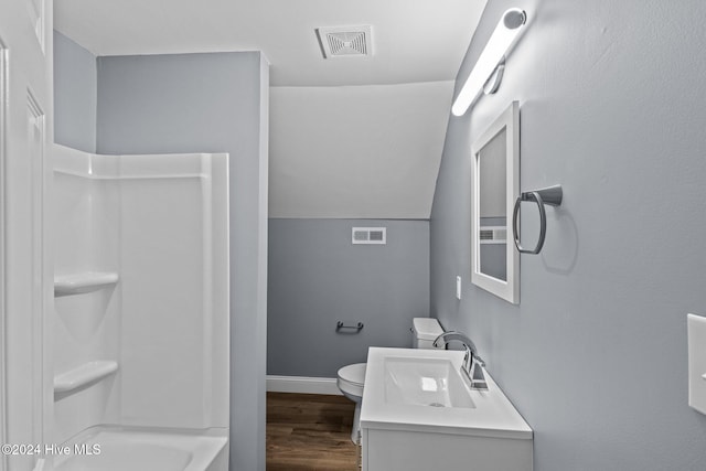 full bathroom featuring wood-type flooring,  shower combination, vaulted ceiling, toilet, and vanity