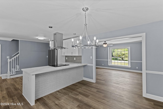 kitchen featuring kitchen peninsula, dark hardwood / wood-style floors, hanging light fixtures, and wall chimney range hood