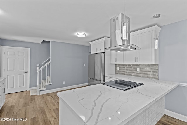 kitchen with island exhaust hood, stainless steel fridge, black electric stovetop, white cabinets, and light wood-type flooring