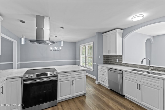 kitchen featuring island exhaust hood, stainless steel appliances, sink, decorative light fixtures, and white cabinetry