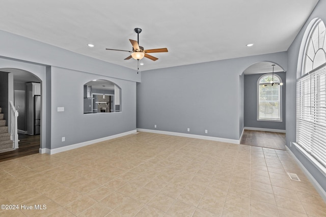 unfurnished room with ceiling fan with notable chandelier