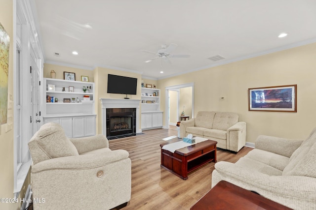 living room with a fireplace, light hardwood / wood-style flooring, ceiling fan, and crown molding