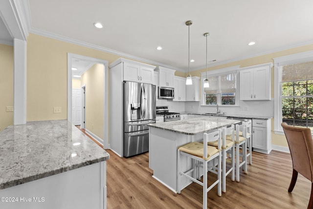 kitchen with appliances with stainless steel finishes, light hardwood / wood-style flooring, white cabinetry, and ornamental molding