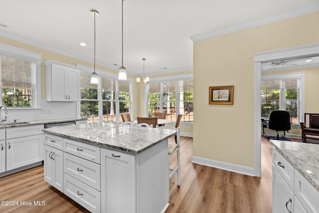 kitchen featuring a center island, a kitchen breakfast bar, crown molding, hardwood / wood-style floors, and white cabinets