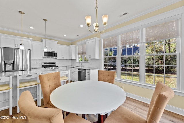 dining room with a chandelier, crown molding, sink, and light hardwood / wood-style flooring