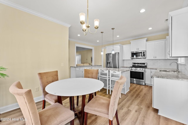 dining room featuring light hardwood / wood-style floors, an inviting chandelier, crown molding, and sink