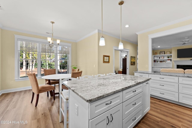 kitchen with white cabinetry, wood-type flooring, and decorative light fixtures