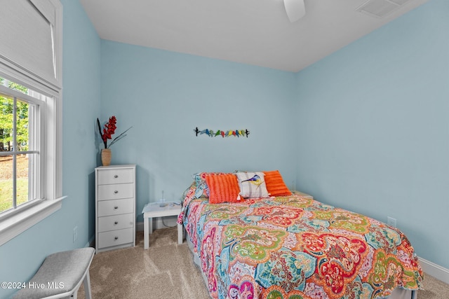 carpeted bedroom featuring multiple windows and ceiling fan