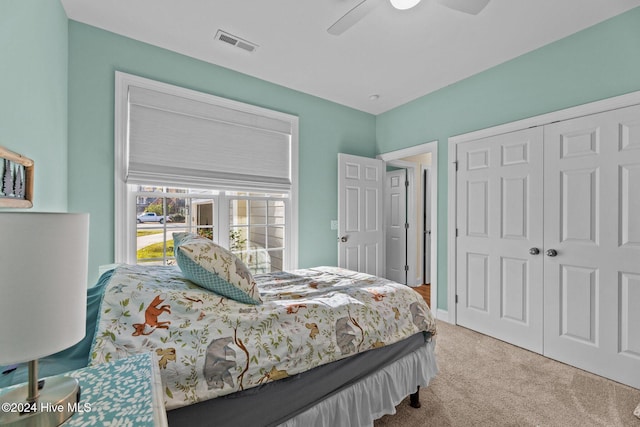 bedroom with ceiling fan, light colored carpet, and a closet