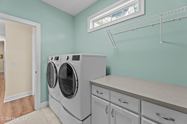 laundry area featuring cabinets, light wood-type flooring, and separate washer and dryer