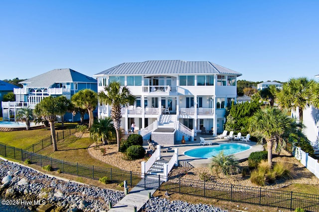 back of property featuring a patio, a balcony, a fenced in pool, and a lawn