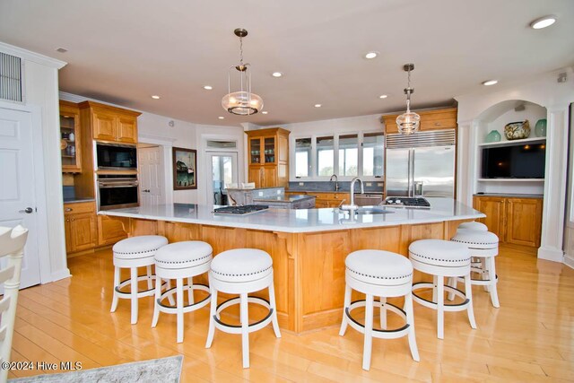 105 Wind Dance Ln, Swansboro, NC 28584 - kitchen with built in appliances, a spacious island, brown cabinets, a sink, and light wood-style floors